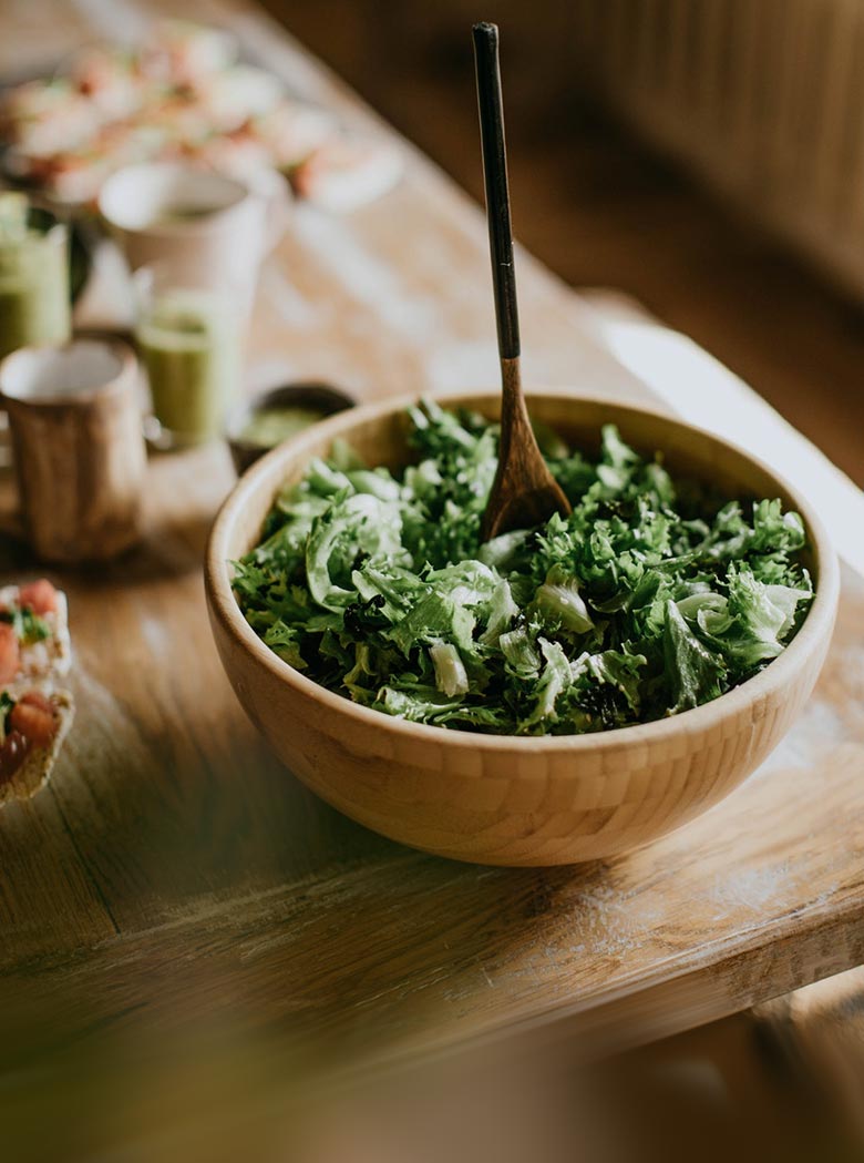 Wooden bowl filled with a salad on a wooden table