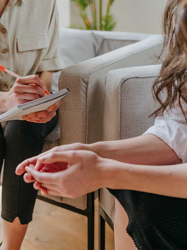 Coaching a woman sitting in a chair and the other women sitting in a chair with a note pad